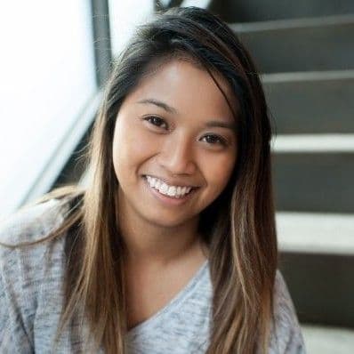 Smiling young woman with long dark hair and a gray shirt looks at the camera.