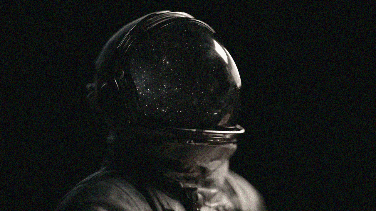 Astronaut in a dark space suit helmet reflecting a starry galaxy.